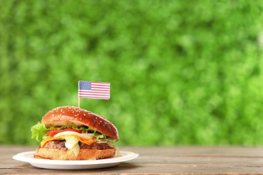 Açık havada Amerikan bayrağı taşıyan lezzetli bir burger, yakın plan. Amerikan Bağımsızlık Günü kutlamaları