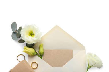 Boş kart, zarf, alyans ve beyaz arkaplanda güzel östoma çiçekleri olan kompozisyon, yakın plan.