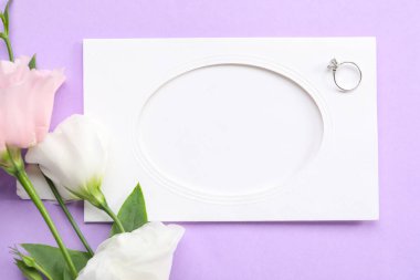 Boş kartlı kompozisyon, nişan yüzüğü ve mor arka planda güzel östoma çiçekleri, yakın plan.