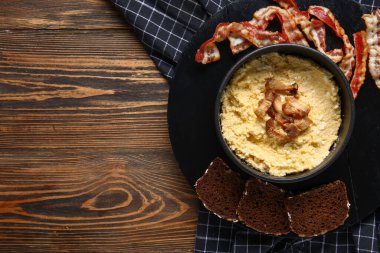 Bir kase lezzetli muz, domuz pastırması ve ahşap arka planda ekmek.