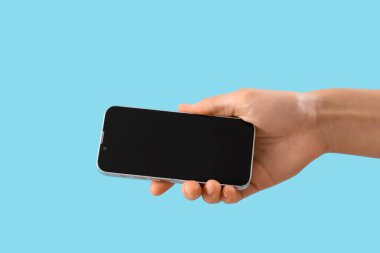 Mavi arka planda boş cep telefonu olan kadın
