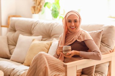 Evde bir fincan kahvesi olan genç Müslüman kadın.