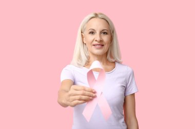 Pembe arka planda kurdeleli olgun bir kadın. Göğüs kanseri farkındalığı konsepti