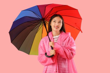 Pembe arka planda şemsiyesi olan Asyalı güzel bir kadın.