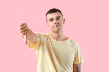 Pembe arka planda hoşlanmadığını gösteren genç bir adam.