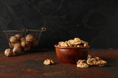 Bir kase lezzetli ceviz masada, siyah duvara karşı.