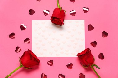 Kalpleri olan boş bir kart ve pembe arka planda kırmızı güller. Sevgililer Günü kutlaması