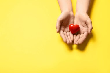 Sarı arka planda kırmızı kalpli kadın elleri