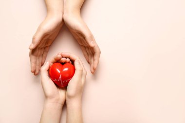 Pembe arka planda kırmızı kalpli kadın ve çocuğun elleri