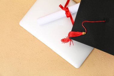 Diplomalı havan mermisi tahtası ve kahverengi arka planda modern laptop.