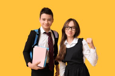 Sarı arka planda not defterleri olan sevimli okul çocukları.