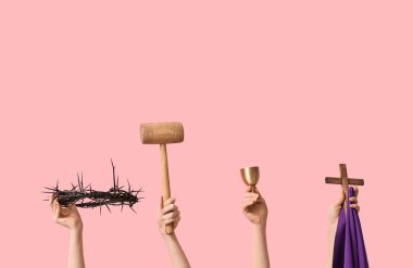 Dikenli taç, tokmak, bardak ve pembe zemin üzerinde ahşap haç olan kadın elleri. İyi Cuma konsepti