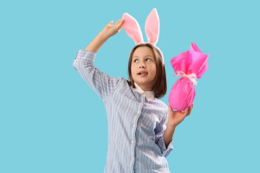 Paskalya tavşanı kulakları ve mavi arka planı olan sevimli küçük bir kız.