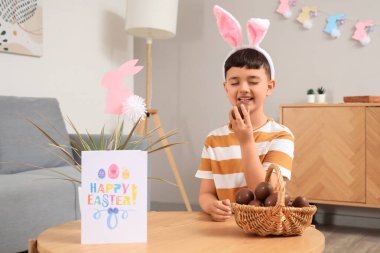 Paskalya evi için dekore edilmiş çikolata yumurtası sepeti ile tavşan kulaklı şirin bir çocuk.