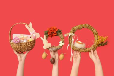 Paskalya bayramı çelenkleri ve kırmızı arka planda sepeti olan kadın eller.