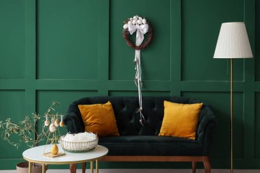 Şık oturma odasının içinde kanepe, masa ve Paskalya çelengi var.