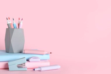 Keçeli kalemleri ve pembe arka plan kitabı olan kalem tutucu