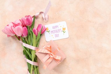 Mesajlı tebrik kartı Mutlu Anneler Günü, güzel pembe laleler ve bej arka planda hediye kutusu.