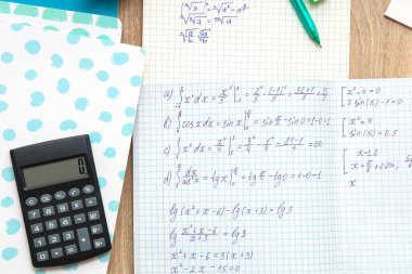 Matematik formülleri, not defterleri ve hesap makinesi olan defterler ahşap masaya, yakın plan