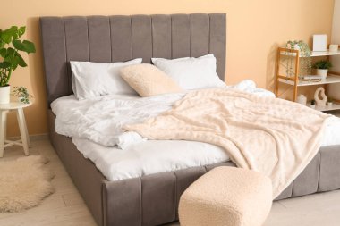 Rahat bir yatak, puf ve bitki yatak odasında.