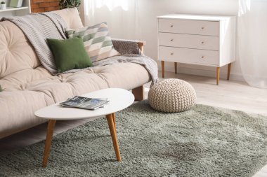 Rahat bir kanepe, puf, sehpa ve oturma odasının içindeki çekmeceler.