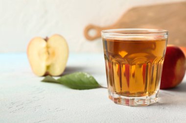 Işık masasında bir bardak taze elma suyu.