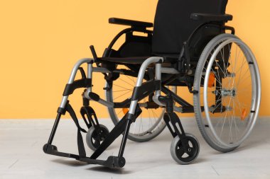 Turuncu duvarın yanındaki boş tekerlekli sandalye.