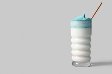 Beyaz arkaplanda saman bulunan bir bardak mavi dalgona matcha latte.