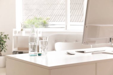 Işık ofisindeki masada cam kaplı bir şişe su.