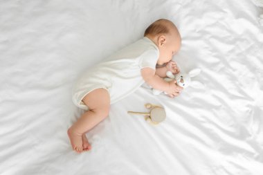 Oyuncak tavşancığı olan şirin bir bebek. Yatakta uyuyor.