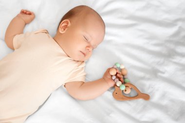 Çıngıraklı tatlı küçük bebek yatakta uyuyor, üst tarafta.