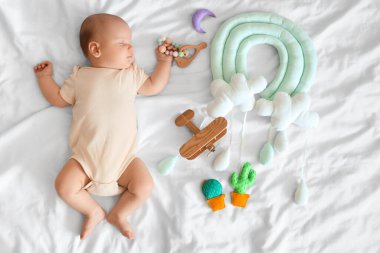 Yatakta uyuyan oyuncakları olan şirin bir bebek.