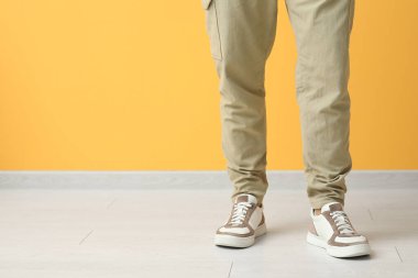 Sarı duvarın yanında şık ayakkabılı genç adam, yakın plan.