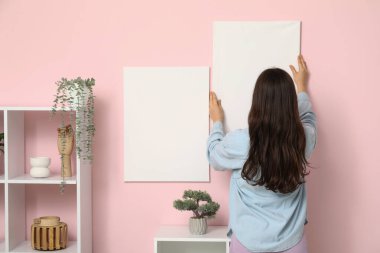 Evdeki bej duvara boş poster asan genç bir kadın. Arka plan