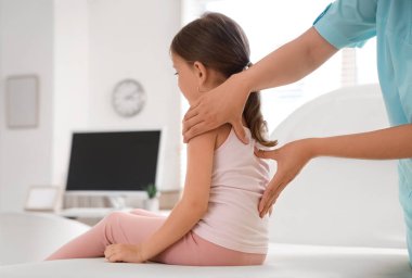 Kadın osteopat klinikte küçük bir hastayla çalışıyor.
