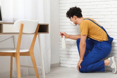 Erkek temizlikçi ofisteki köşe başındaki küfleri temizliyor.