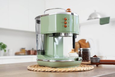 Mutfaktaki masada bir kavanoz fasulye ile modern yeşil kahve makinesi.