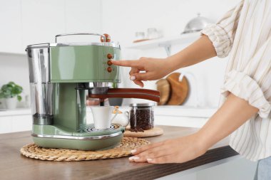 Modern yeşil makineyle kahve yapan genç ve güzel bir kadın, yakın plan.