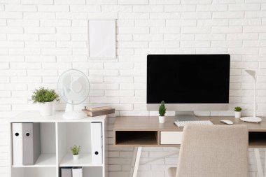 Ofiste modern bilgisayar ve elektrikli vantilatör ile rahat çalışma alanı