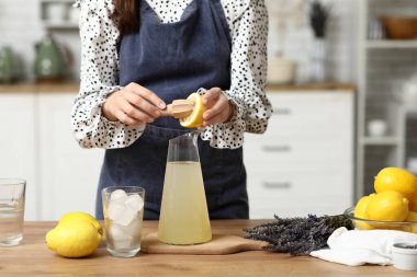 Mutfaktaki masada lavantalı limonata hazırlamak için limon sıkan genç kadın.