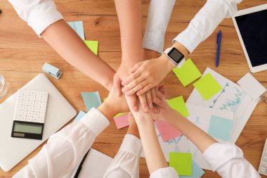 Ofiste yapılan toplantıda birlik sembolü olarak el ele tutuşan iş adamları.