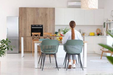 Masada oturan genç bir kadın yemek odası, arka manzara...