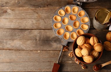 Lezzetli ceviz şekilli kurabiyeler, kaynamış süt ve ahşap zemin üzerinde pişirme formu.