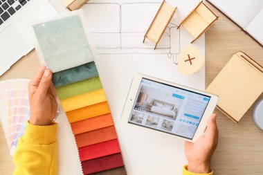 Kumaş örnekleri ve tablet bilgisayarı olan erkek mobilya tasarımcısı.