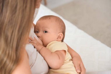 Anne, bebeğini yatak odasında emziriyor.