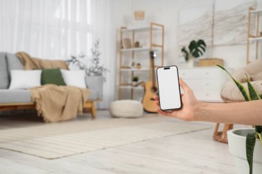 Evde boş cep telefonu olan bir kadın, yakın plan.