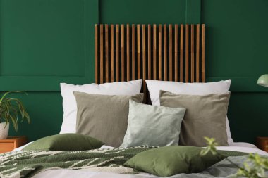 Yeşil duvarın yanında yumuşak yastıklı rahat bir yatak.