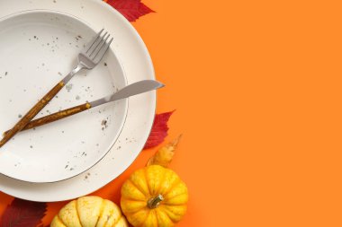 Turuncu arka planda taze balkabaklarıyla ve sonbahar yapraklarıyla güzel bir masa.