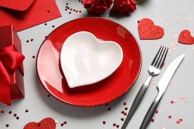 Gri arka planda hediye kutusu, zarf ve kırmızı güllerle güzel bir masa. Sevgililer Günü kutlaması