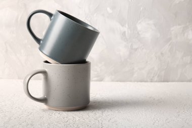 Beyaz duvarın yanındaki masada seramik kupalar